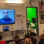 Students in a classroom watching a live videoconference.