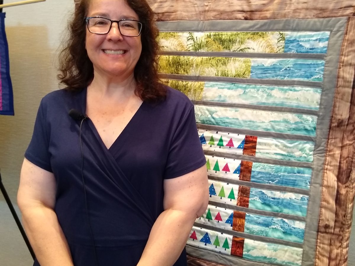 Woman standing in front of hanging quilt artwork