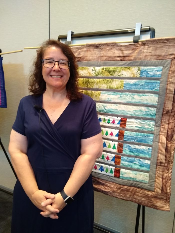 Woman standing in front of hanging quilt artwork