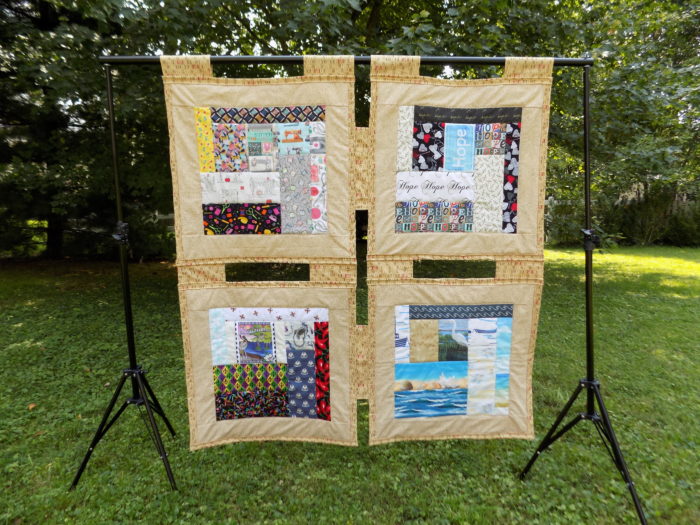 Image of a quilt hanging on a rack outside with four main panels