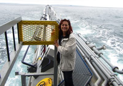 Woman standing on Research Platform (Floating Instrument Platform) in a large body of water with the horizon in the background.