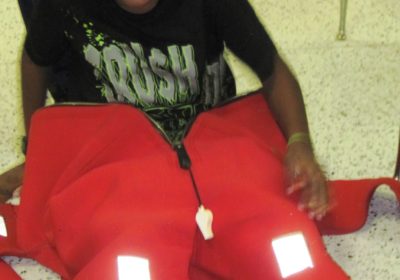 A child is sitting on the floor wearing an immersion suit.