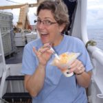 Woman on a ship eating a dessert.