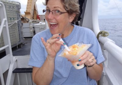 Woman on a ship eating a dessert.