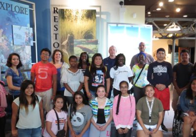 A group of adults and students gathered in a museum.