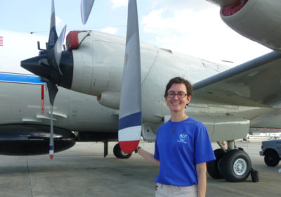 A woman stands by a Hurricane Hunter aircraft.