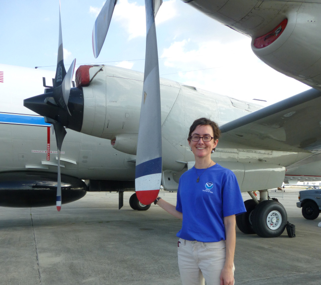 A woman stands by a Hurricane Hunter aircraft.