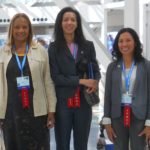 Three women stand together with Judge ribbons.