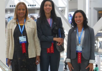 Three women stand together with Judge ribbons.