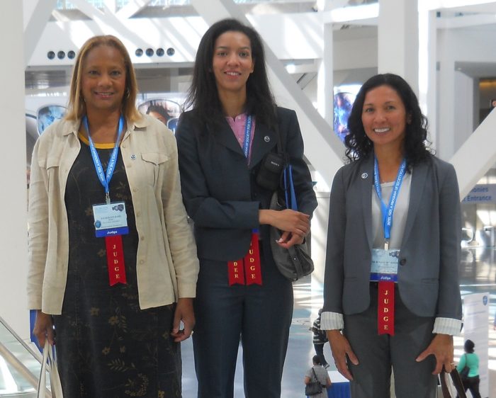 Three women stand together with Judge ribbons.
