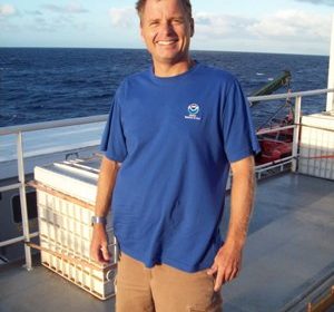 A man on a ship with the water in the background.