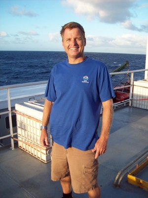 A man on a ship with the water in the background.