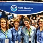 Four women stand in front of a NOAA Education sign.