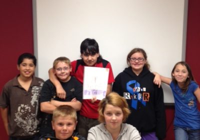 Seven students gathered together while one of them holds a picture.