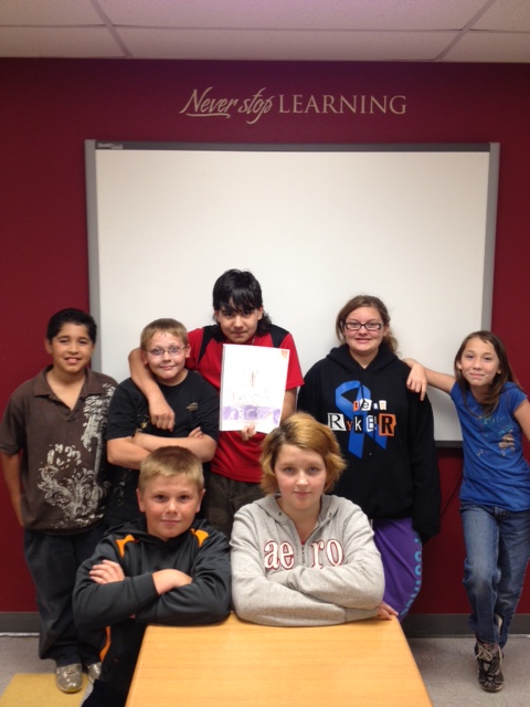 Seven students gathered together while one of them holds a picture.