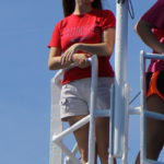 A woman stands at the bow of a ship.