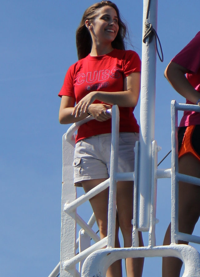 A woman stands at the bow of a ship.