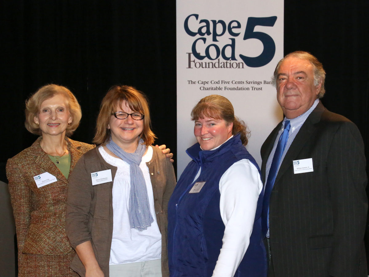 Three women and one man stand in front of a Cape Cod 5 Foundation sign.