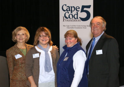 Three women and one man stand in front of a Cape Cod 5 Foundation sign.