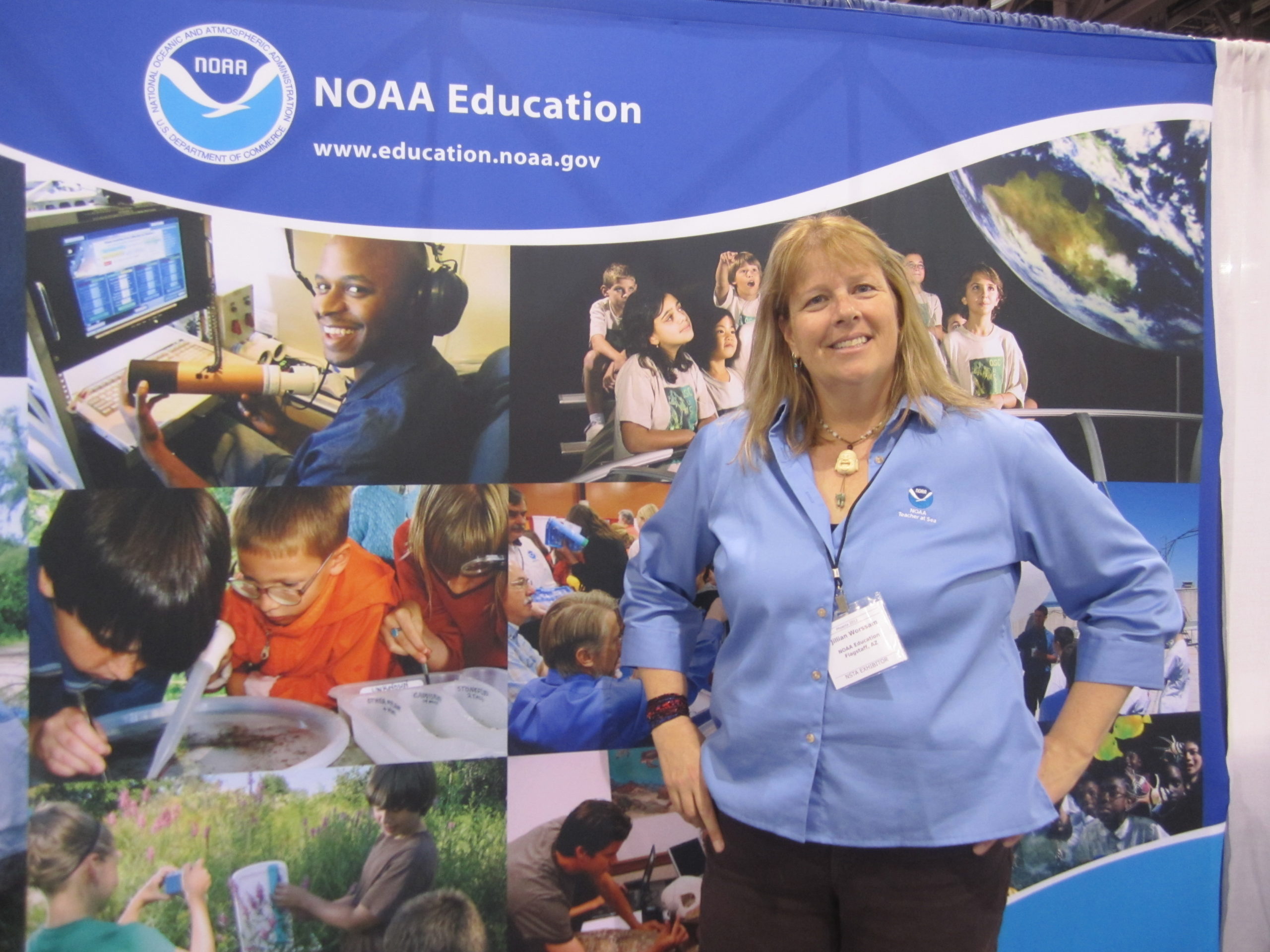 A woman stands in front of a NOAA Education sign.