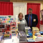 A woman and a man stand behind a NOAA Teacher at Sea display table.