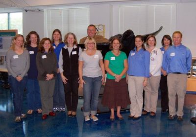 A group of people stand together in a classroom