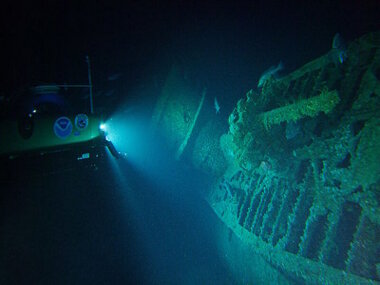 Remotely Operated Vechicle underwater shining spotlight on a submerged wreck