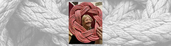 Photo of woman displaying repurposed rope wreath against black & white rope background