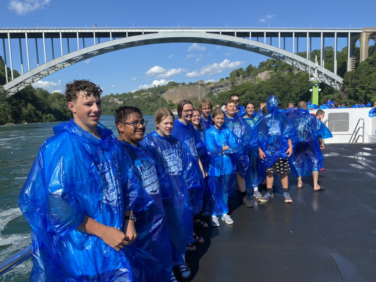 Students in blue raincoats under a bridge at Niagara Falls